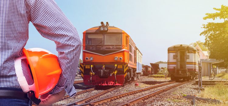 engineer holding safety helmet with orange diesel engine locomotive passenger train background