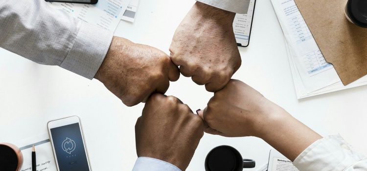 Quattro pugni uno vicino all'alto per simboleggiare che insieme si può raggiungere il successo aziendale.